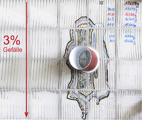 <p>Bild 2  Erster Versuch mit Fliesenbett nach vereinfachtem Verlegeverfahren: Die Linien der Filzmarker zeigen die Grenzen zwischen trockenem und nassem Fliesenbett zu verschiedenen Zeiten. Oben rechts stehen die Gewichte des Prüfkörpers am Anfang und während der Trockenphase.</p> - © OFI