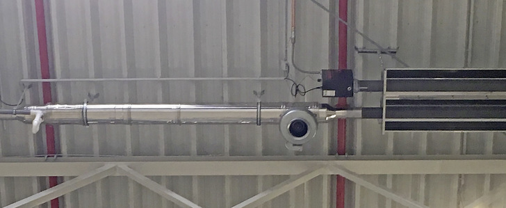 Bild 1: Dunkelstrahler mit emissionsarmem Gas-Gebläsebrenner beim Logistikunternehmen Segro Logistics. Das Strahlungsband (rechts) ist rund 13 m lang, links befindet sich im Anschluss an den U-Rohr-Strahler der Rohrbündel-Wärmeübertrager aus Edelstahl für die Brennwertnutzung. - © Bild: Vacurant
