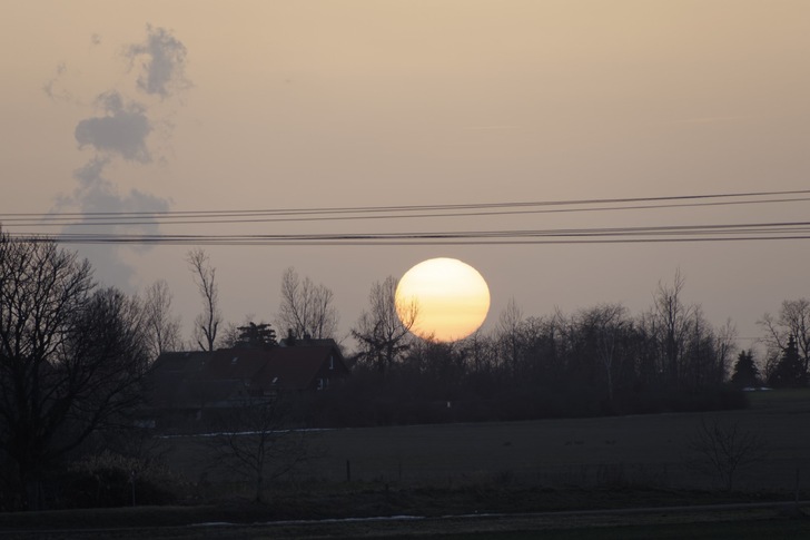 Saharastaub sorgte dafür, dass die Sonne am 23. Februar 2021 eher blass unterging. Der Farbverlauf von weiß nach gelb deutet darauf hin, dass sich in der untersten Luftschicht Saharastaub mit kleineren Partikeln aus der Luftverschmutzung mischt.
