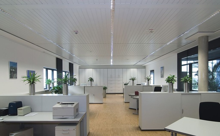 Lüftungsauslässe und Beleuchtungselemente wurden in die Zehnder Como Deckensegel integriert. Die Abluft wird durch eine Schattenfuge zwischen Deckensegel und Randfries abgeführt. Zudem konnten in Wallerstein allein durch die Installation der Kühl- und Heizelemente mit ihren akustischen Dämmfähigkeiten die Anforderungen an die Schallemissionsminderung erfüllt werden.