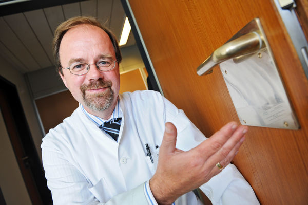 Prof. Dr. Jörg Braun mit einer Kupfer-Türklinke in der Asklepios Klinik Wandsbek - © Asklepios Kliniken Hamburg GmbH
