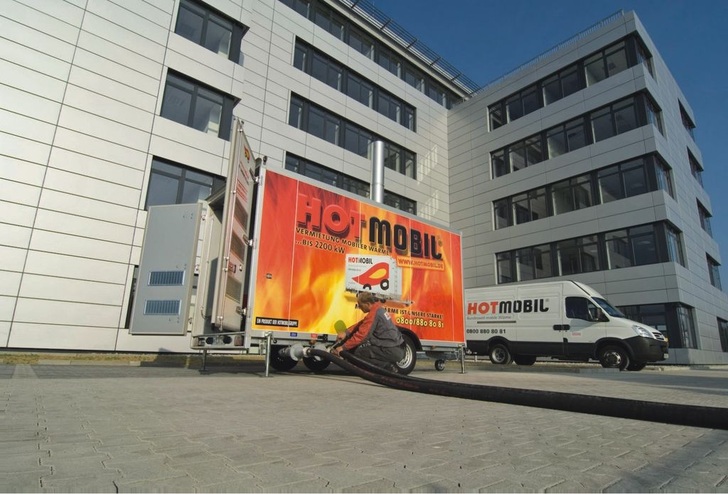 Mobile Heizzentrale von Hotmobil im Einsatz für die Wärmeversorgung eines Wohngebäudes.