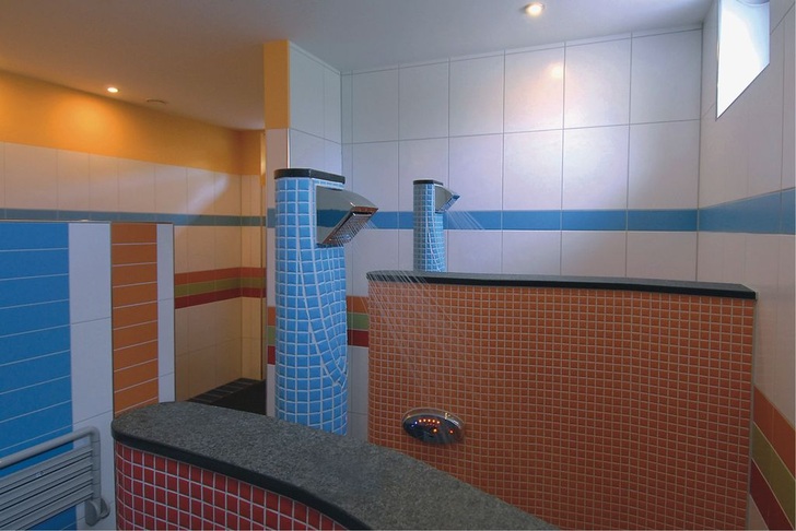 Im Kinderbad der Luxus-Campinganlage Eifel-Camp sprühen eigens konzipierte Duschen das Wasser in Richtung Wand. Für die Eltern heißt das: „Duschen, ohne nass zu werden“. - © Eifel-Camp
