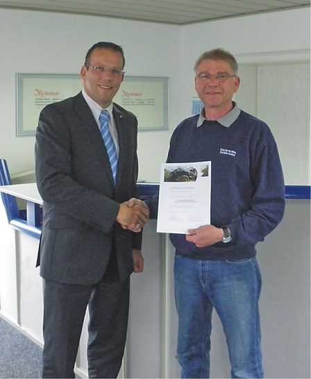 Dieter Uebelmann überreicht die Gewinnurkunde für ein Offroad-Fahrertraining an Wolfram Thoma.