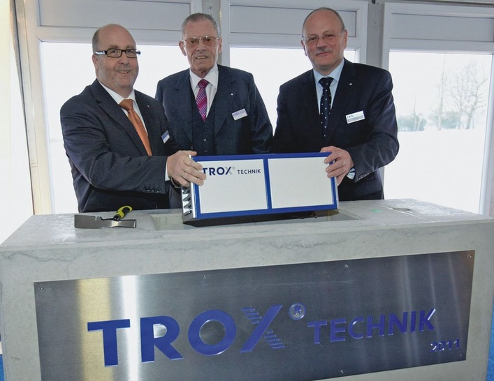 Heinz Trox (Mitte) legt gemeinsam mit Lutz Reuter (links), und Udo Brinkmann, beide Geschäftsführer der Trox GmbH, ein miniaturisiertes RLT-Gerät in den Grundstein ein.