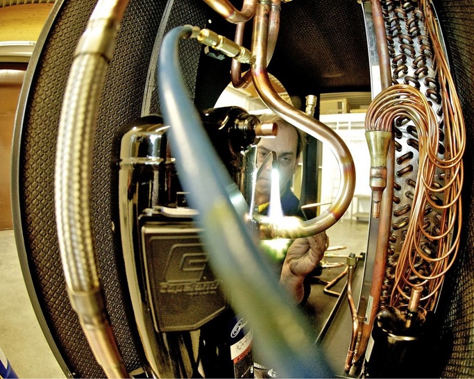 Bartl Wärmepumpen: Innenansicht einer Luft/WasserWärmepumpe, bei der gerade der Verdichter eingelötet wird. - © Bartl Wärmepumpen / Uwe Röder
 Bartl Wärmepumpen: Innenansicht einer Luft/WasserWärmepumpe, bei der gerade der Verdichter eingelötet wird.