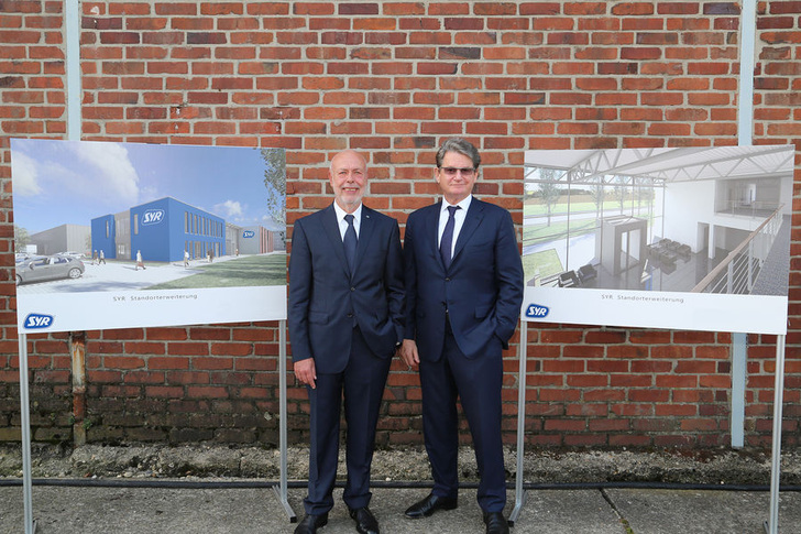 SYR erweitert seinen Standort. Die Firmenspitze, Harald Sasserath (links), Inhaber und Sohn von Firmengründer Hans Sasserath, und Geschäftsführer Willi Hecking präsentiert die Entwürfe der neuen Gebäude.