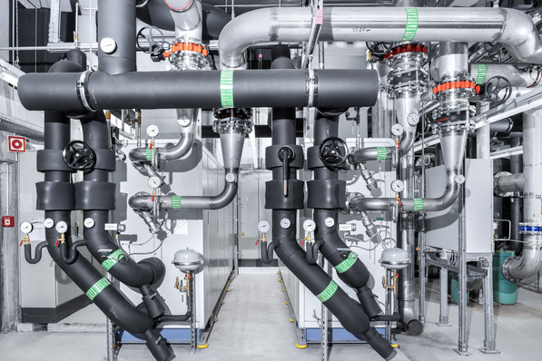  Bild 1 An gleicher Stelle wie die vorherigen R134a-Maschinen stehen in der Technikzentrale heute zwei Flüssigkeitskühlsätze mit R717 als Kältemittel. Hier die Anschlussseite mit der neuen Verrohrung zum Kühlturm und isoliert zum Kaltwassernetz für die Versorgung des Gebäudes.