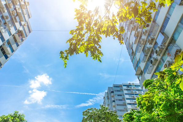 „Moderne Hochhausfassaden mit integrierten photovoltaischen Solarpanels und umgebender Begrünung, symbolisieren die Zukunft der digitalisierten und elektrifizierten Gebäudetechnik bei strahlendem Sonnenschein. - © Quality Stock Arts - stock.adobe.com