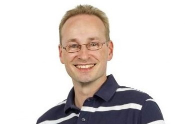 Optimierter, themenrelevanter Alt-Text: „Porträt eines lächelnden Ingenieurs mit Brille, der vor neutralem Hintergrund steht – Symbolbild für Digitalisierung und intelligente Gebäudetechnik in der TGA-Planung.“. - © GV