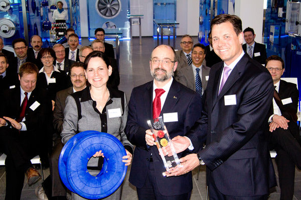 Laudator Axel Hepelmann (rechts) überreicht Ziehl-Abegg-Technikvorstand Norbert Schuster den Preis Ausgewählter Ort im “Land der Ideen“. Christine Montigel vom “Land der Ideen“ zeigt das extrem leise und energiesparende Lüfterrad Cpro.