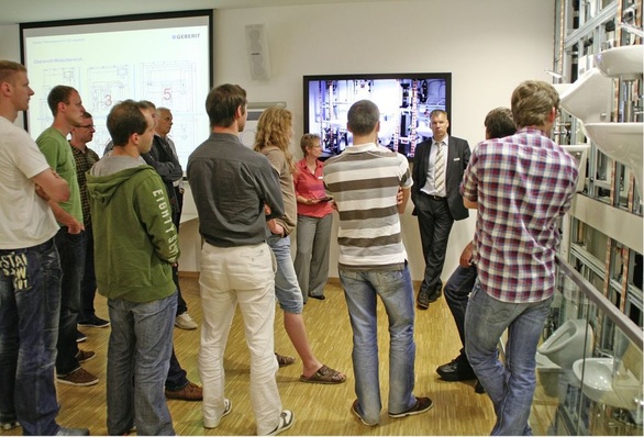 Teilnehmer der HTW-Exkursion an der Installationswand bei Geberit.