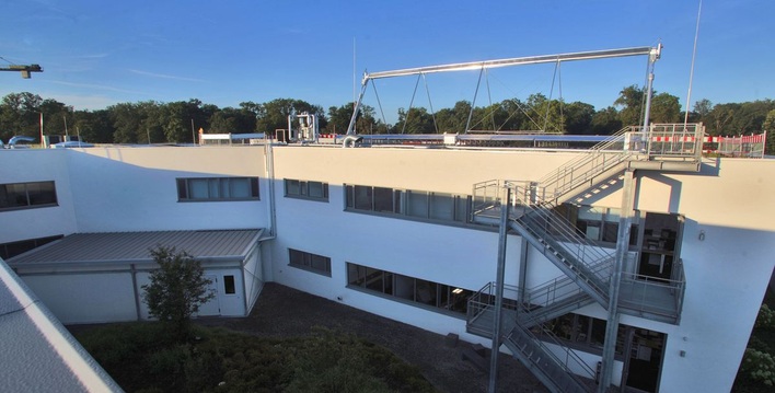 Installation der Versuchsanlage bei Kramer. Im Innenhof steht der Kühlraum, auf dem rechten Dach befinden sich links die Absorptionskältemaschine und rechts der Fresnel-Solarkollektor.