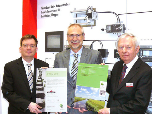 Dr.-Ing. Jürgen Wildeboer, Dipl.-Ing. Hans Peters (IBU) und Dipl.-Ing. Werner Wildeboer bei der Übergabe von Umwelt-Produktdeklarationen für Brandschutzklappen (v.l.).