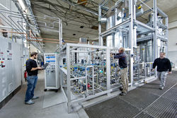 250-kW-Power-to-Gas-Anlage. Links: ZSW-Forscher kontrollieren die Gasmischung. Im Hintergrund die Methanisierungsanlage. Rechts: Elektrolyse zur Wasserstoffherstellung. (Quelle: Zentrum für Sonnenenergie- und Wasserstoff-Forschung Baden-Württemberg)